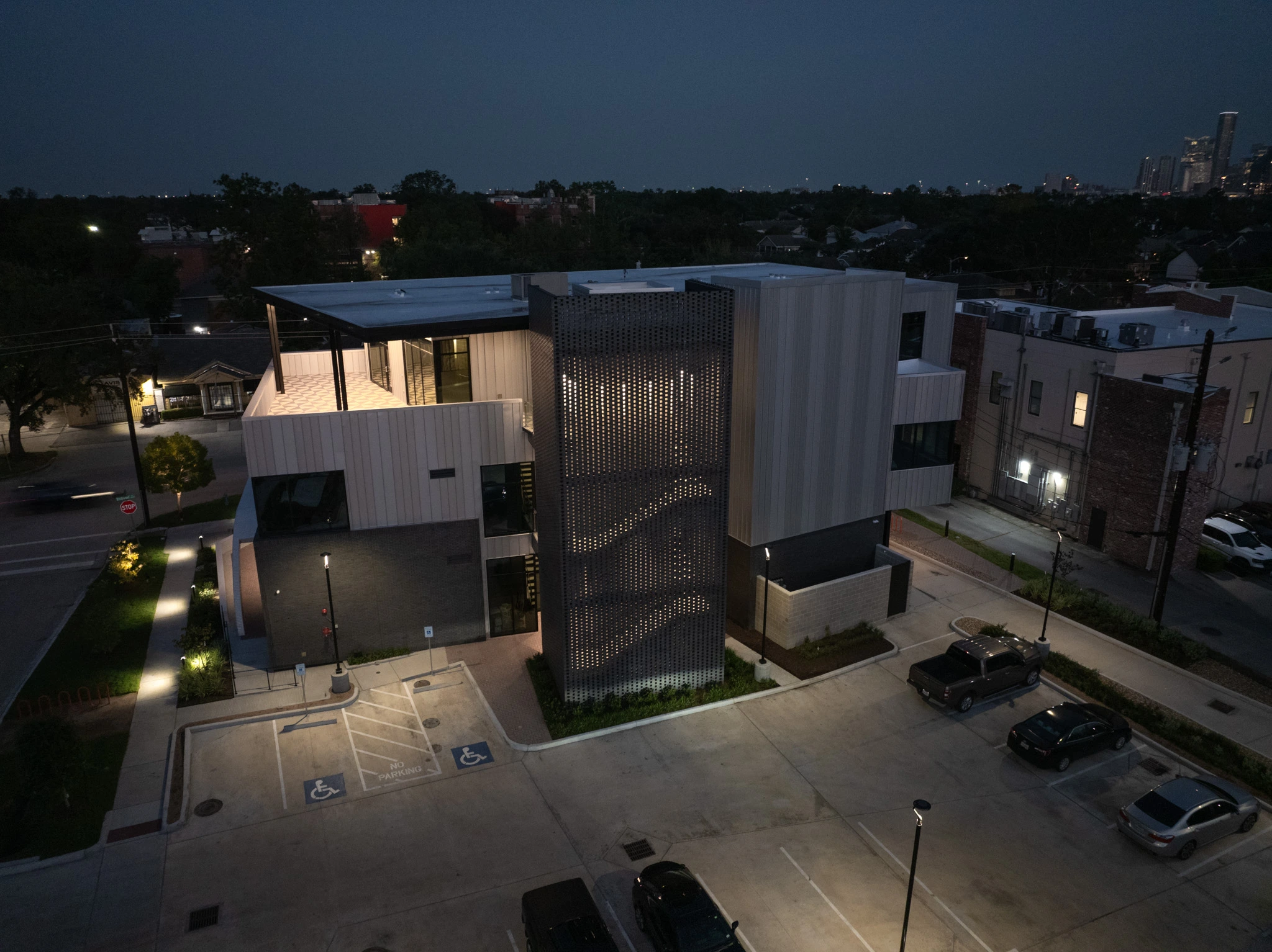 Back view of 1023 Studewood at Night, a modern mixed-use building in The Heights, Houston, featuring retail storefronts, office spaces, large windows, and dedicated parking, ideal for businesses seeking high-visibility locations.